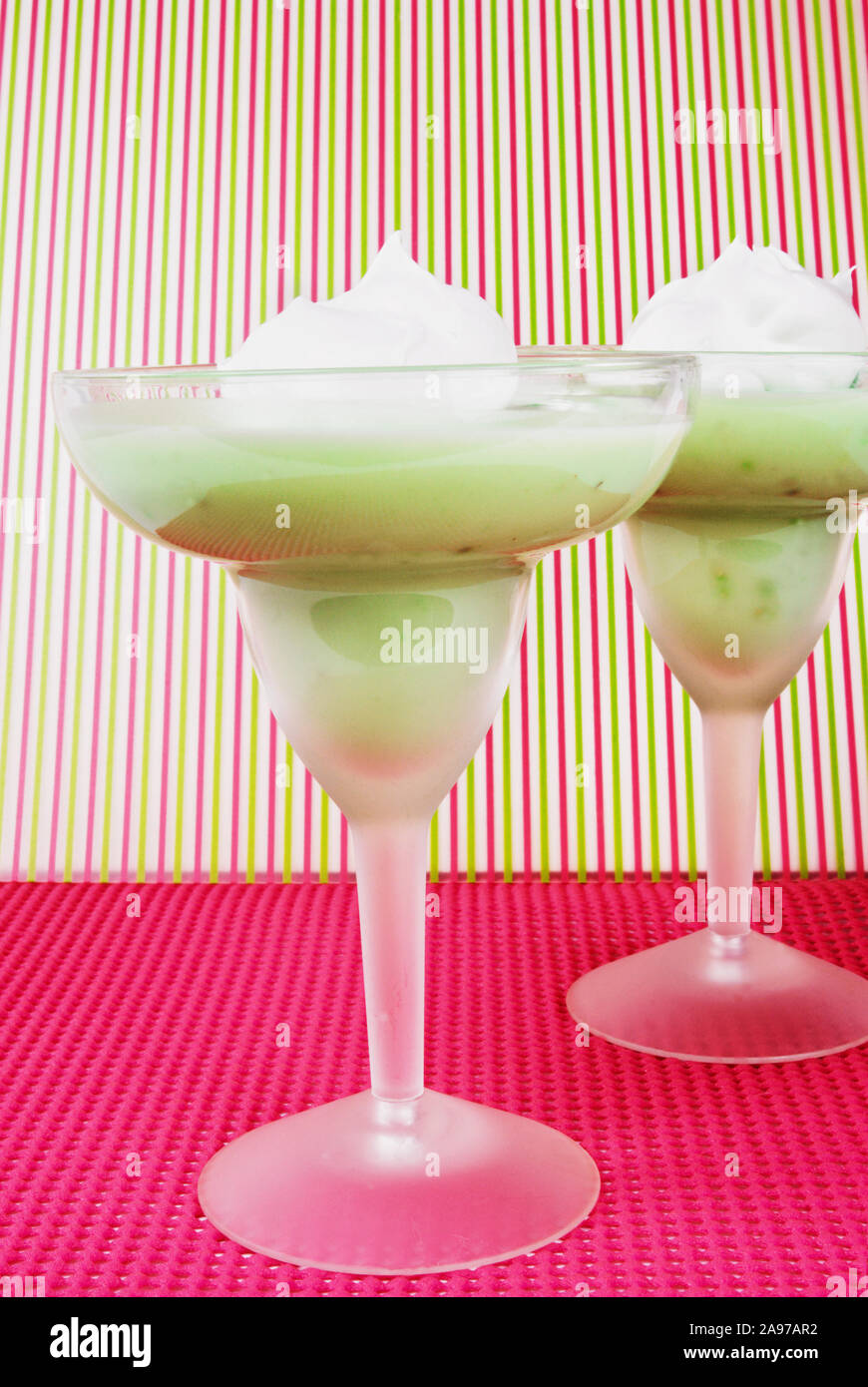 Eye level shot of homemade green colored pistachio pudding with a dollop of whipped cream on top served in two frosted margarita glasses. Naturally li Stock Photo