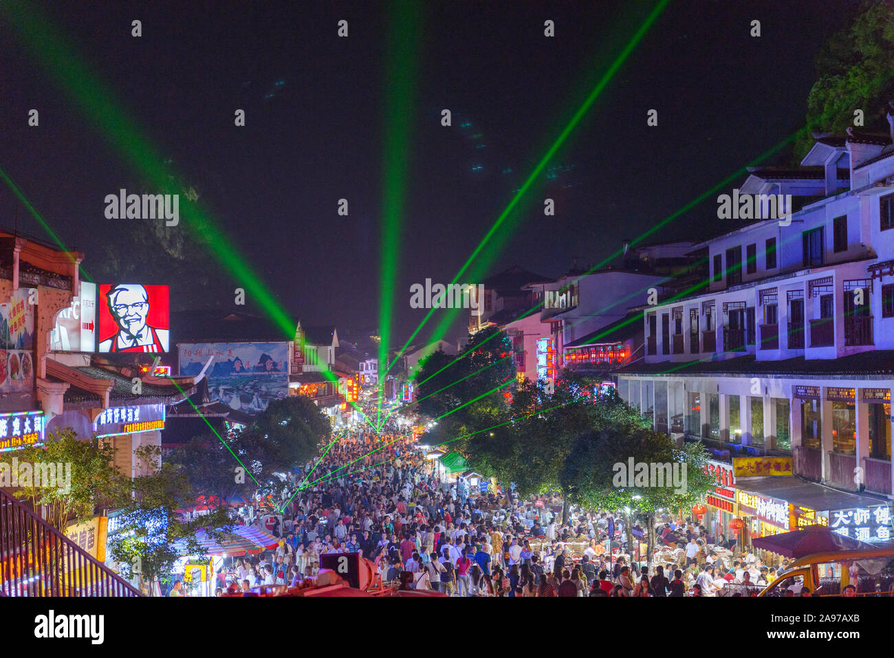 YANGSHUO, CHINA - MAY 27, 2014: Laser lights paint the night sky while large crowds attend an evening festival. Stock Photo