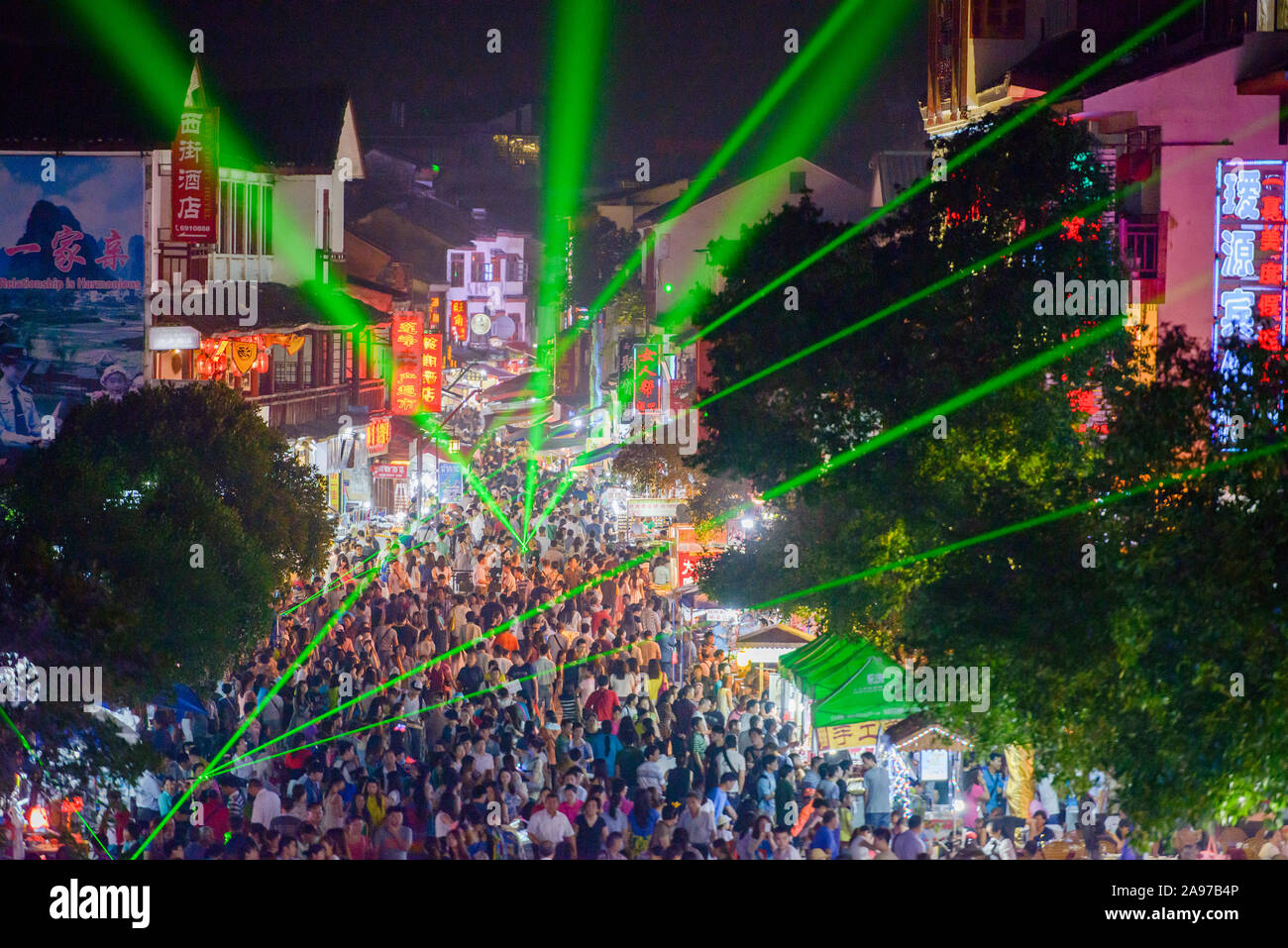 YANGSHUO, CHINA - MAY 27, 2014: Laser lights paint the night sky while large crowds attend an evening festival. Stock Photo