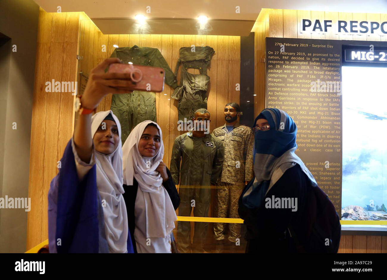 Students take a selfee with statue of Indian pilot Wing  Commander, Abhinandan Varthaman whose plane was shot down over Azad Kashmir, at Pakistan Air Force (PAF) Museum in Karachi on Wednesday, November 13, 2019. Pakistan has  exhibited a statue of an Indian air force pilot, who was taken as prisoner of war after his aircraft was hit and downed in aerial skirmishes early this year. Stock Photo