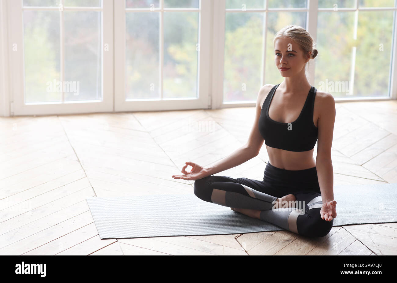 Relaxed yoga girl sitting in lotus pose and meditating at home, no ...