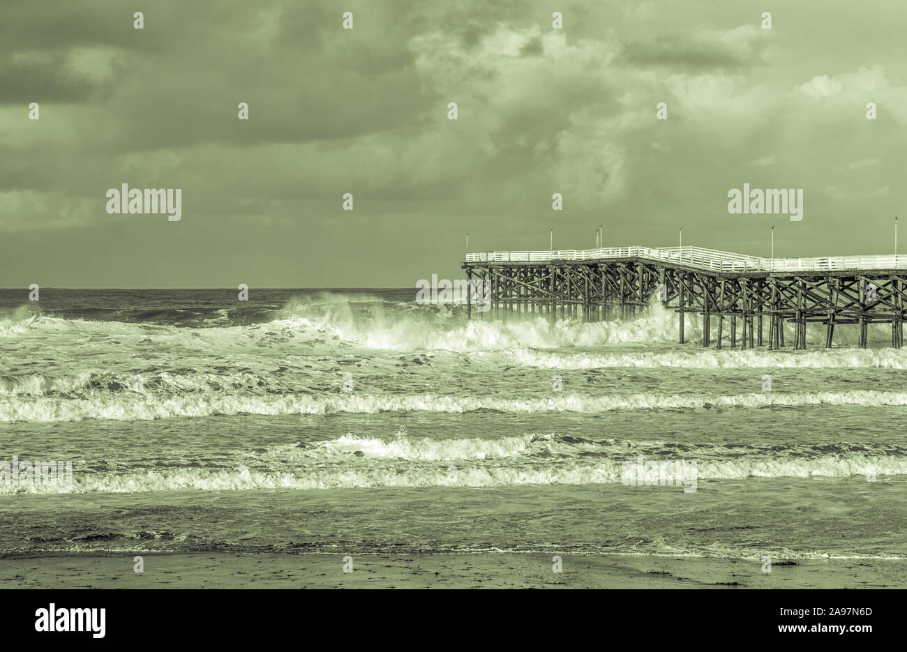Winter surf impacting Crystal Pier. San Diego, California, USA. Presented in duotone. Stock Photo