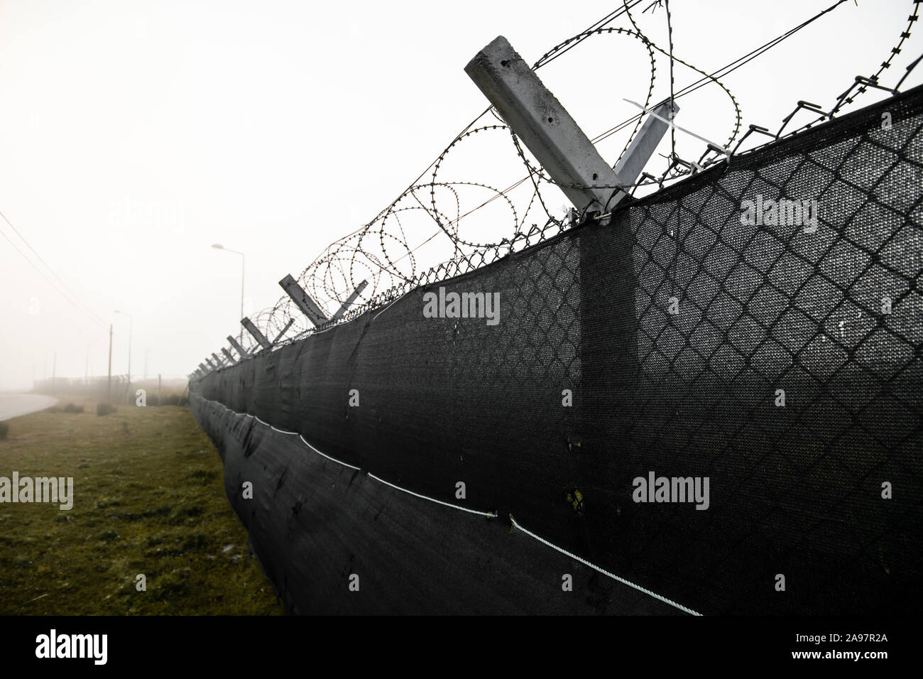 Barbed wire on the fence. Jail Fence Prison in hopeless foggy day Stock Photo