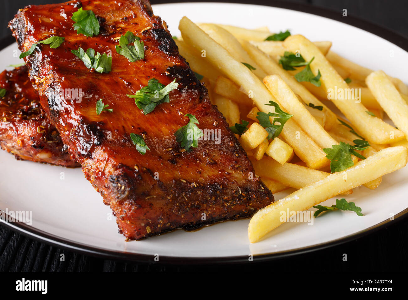 Serving barbecue short ribs with french fries close-up on a plate on the table. horizontal Stock Photo