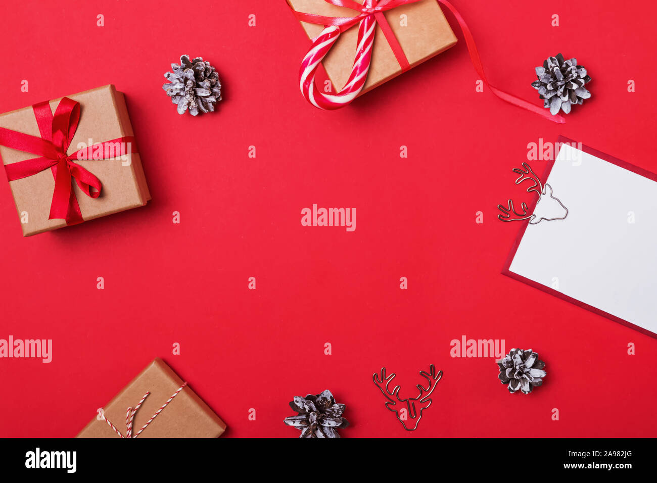 Christmas frame with gift boxes and pine cones on red background Stock Photo
