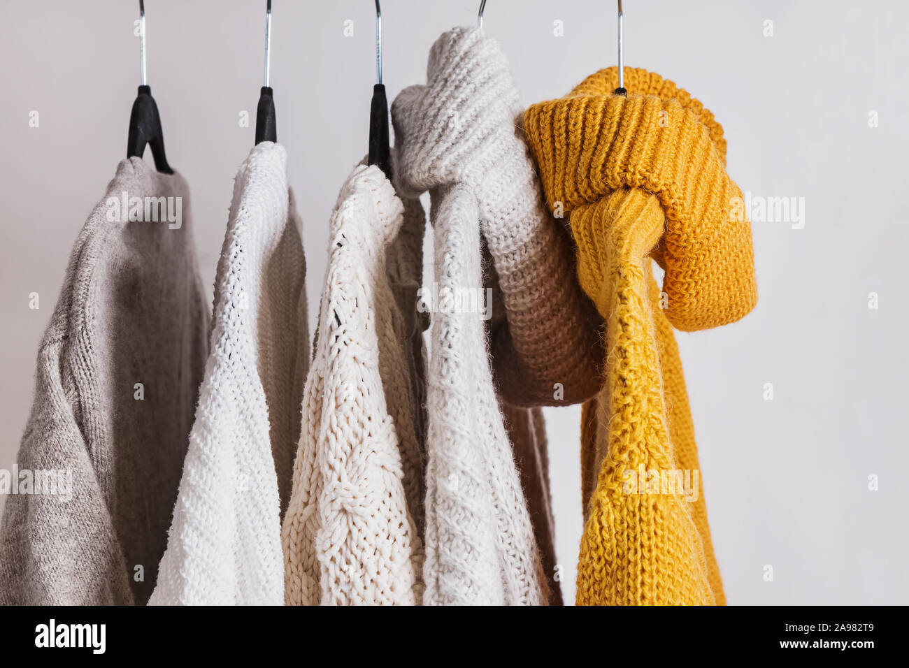 Warm knitted sweaters on the hangers. Stock Photo