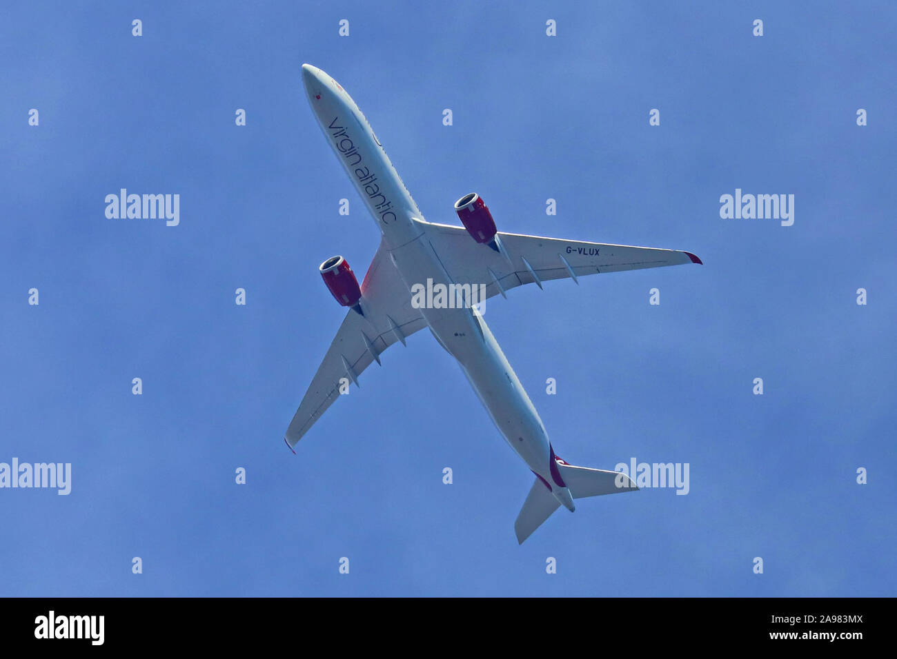 Airbus A350-1041 G-VLUX flying overhead, set against a blue sky background. Stock Photo