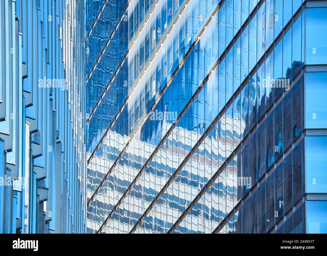 Modern buildings reflected in glass facades, abstract architectural background. Stock Photo