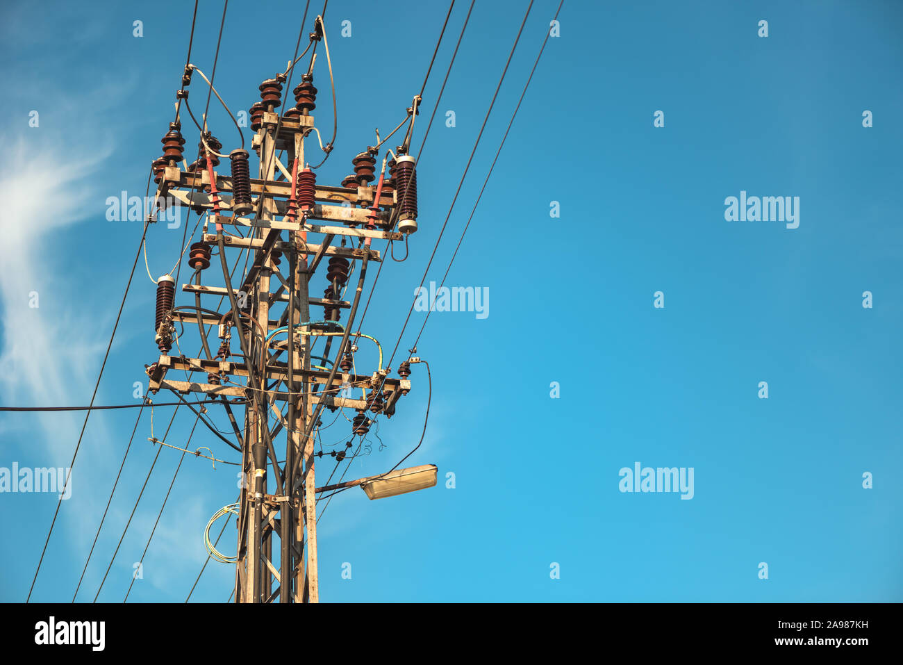Utility pole supporting overhead power line cables against blue sky as copy space Stock Photo