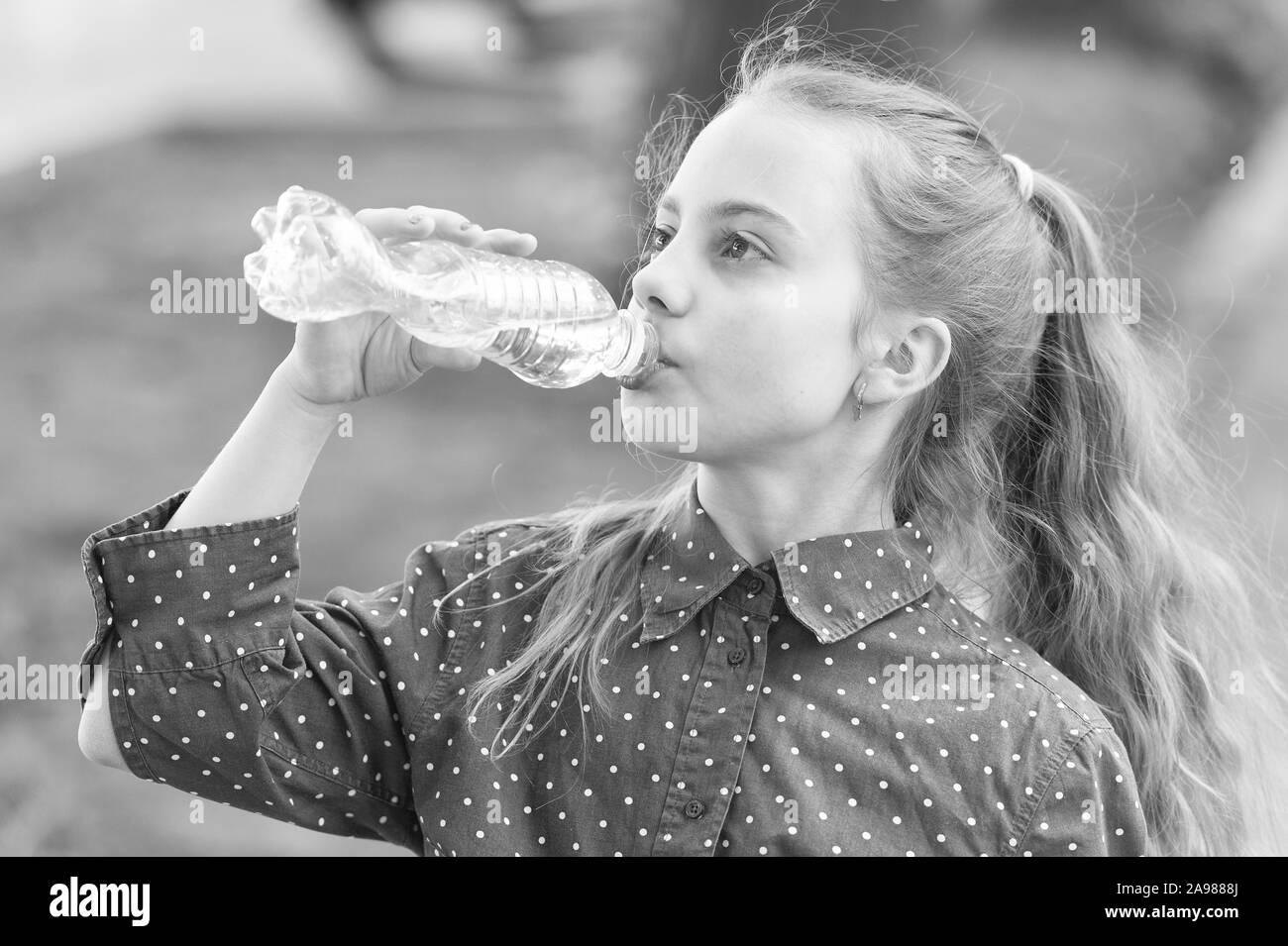 Clean water is a vital resource for human existence. Little girl having a drop of water. Thirsty child drinking fresh water from plastic bottle. Quenching thirst with natural mineral or potable water. Stock Photo