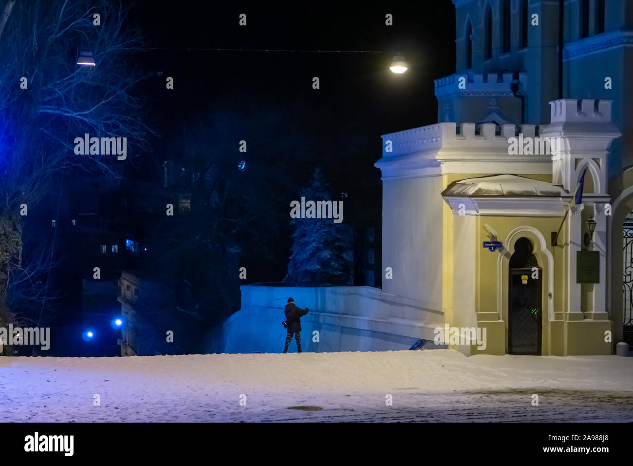 Teen boy imitates a rock musician in a night city. Snow-covered city at night Stock Photo