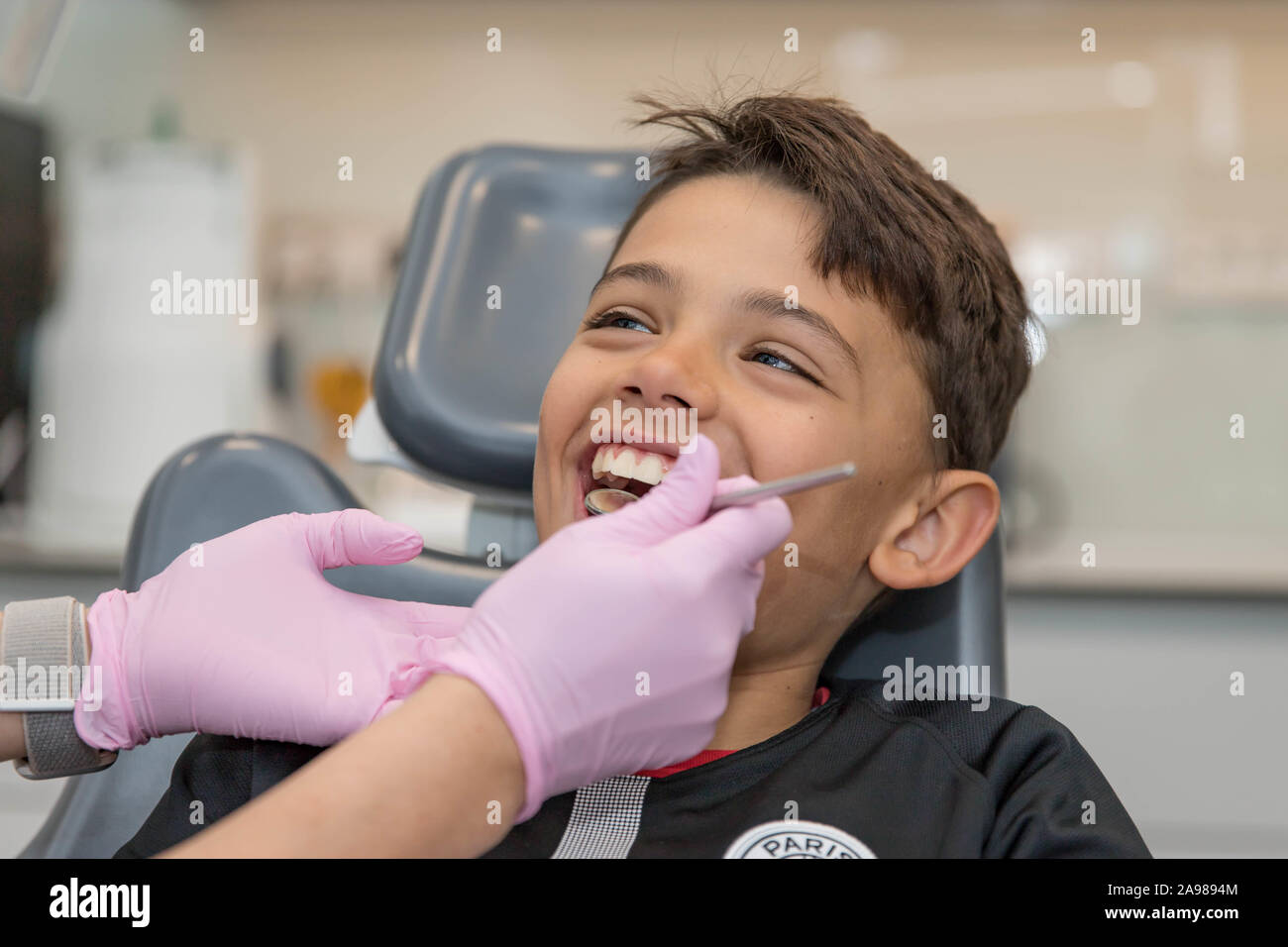Portrait of little boy opening his mouth wide during inspection of oral cavity by dentist. Stock Photo