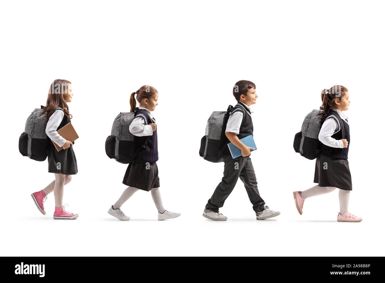 Full length profile shot of schoolchildren in uniforms walking in line isolated on white background Stock Photo