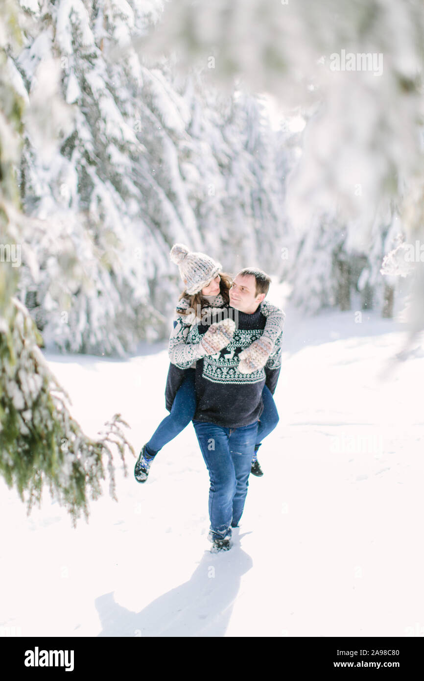 Couple walking in snowy field piggyback Stock Photo - Alamy