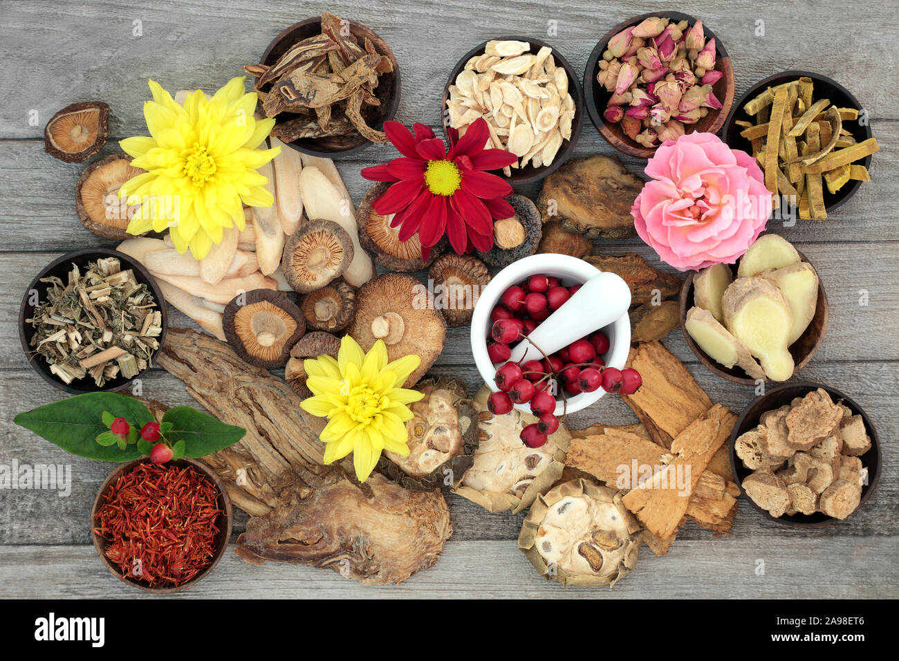Traditional Chinese herbs and flowers used in herbal medicine with a mortar and pestle on rustic