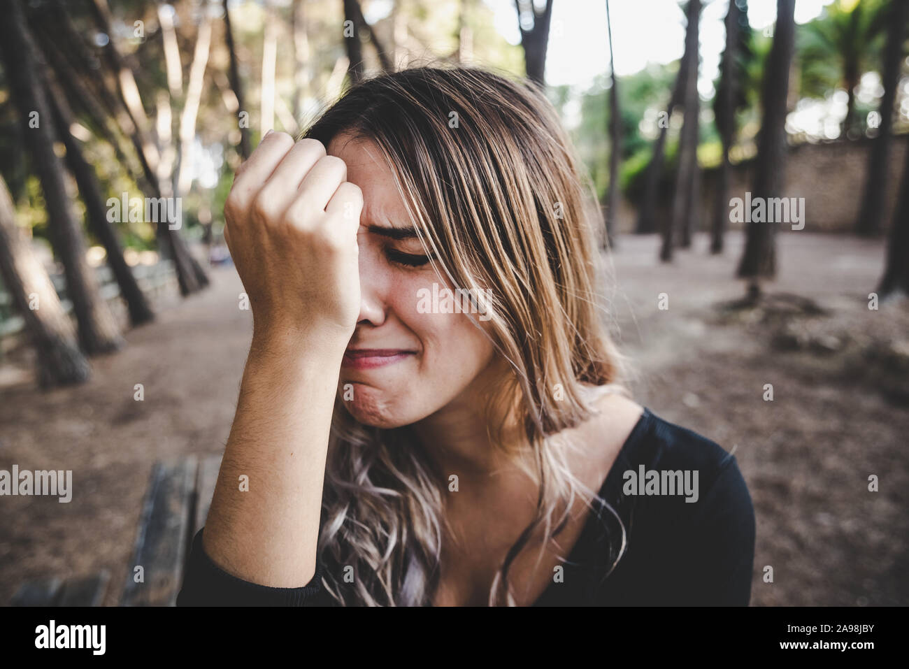 Beautiful woman's face sobbing in disgust as she rests her head on her hand. Stock Photo
