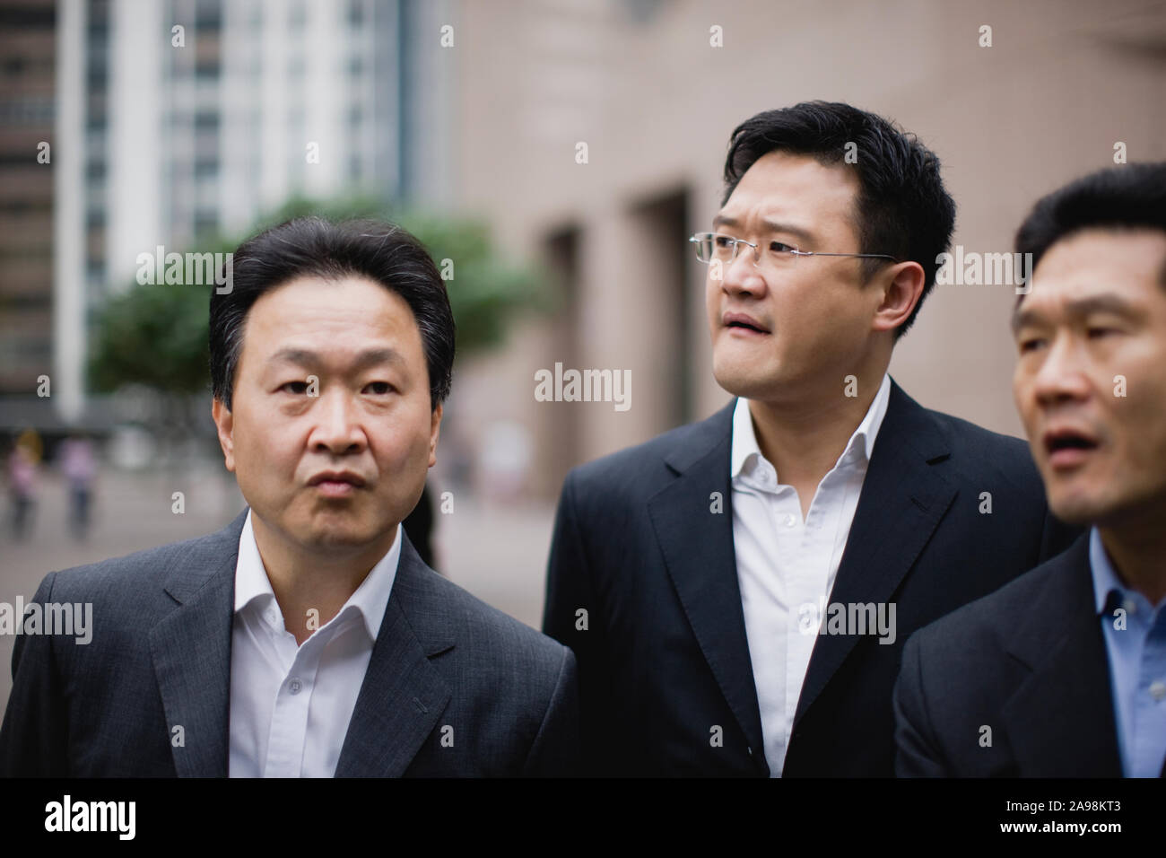 Three businessmen standing next to each other in the city Stock Photo ...