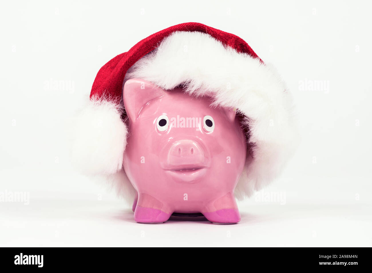 Little Christmas piggy bag with festive hat and white background. Stock Photo