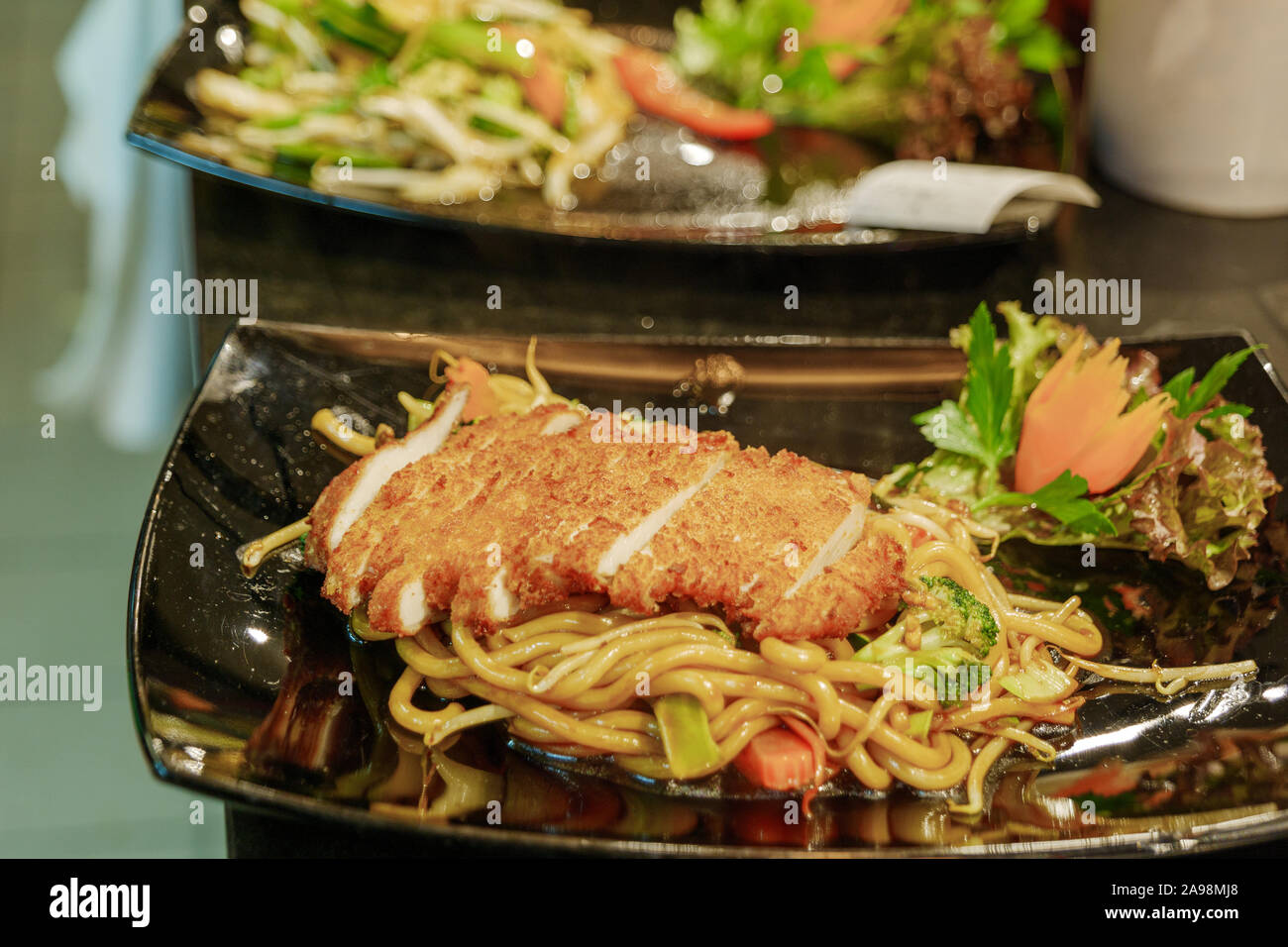 Top view of Asian stir fry egg noodle with crispy chickens serve on