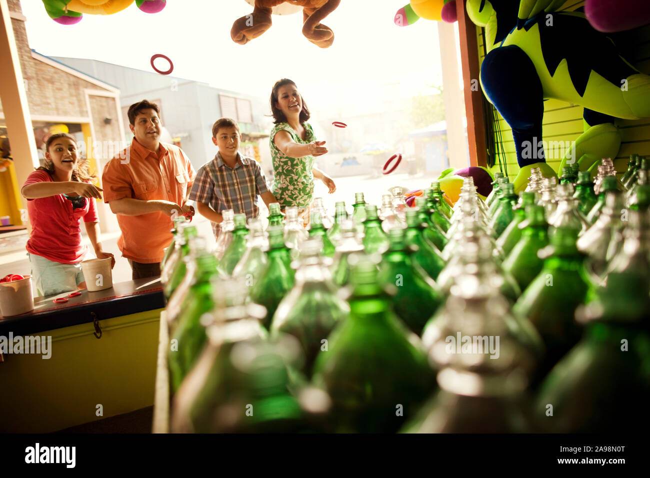 Smiling family playing a bottle toss game at an amusement park Stock