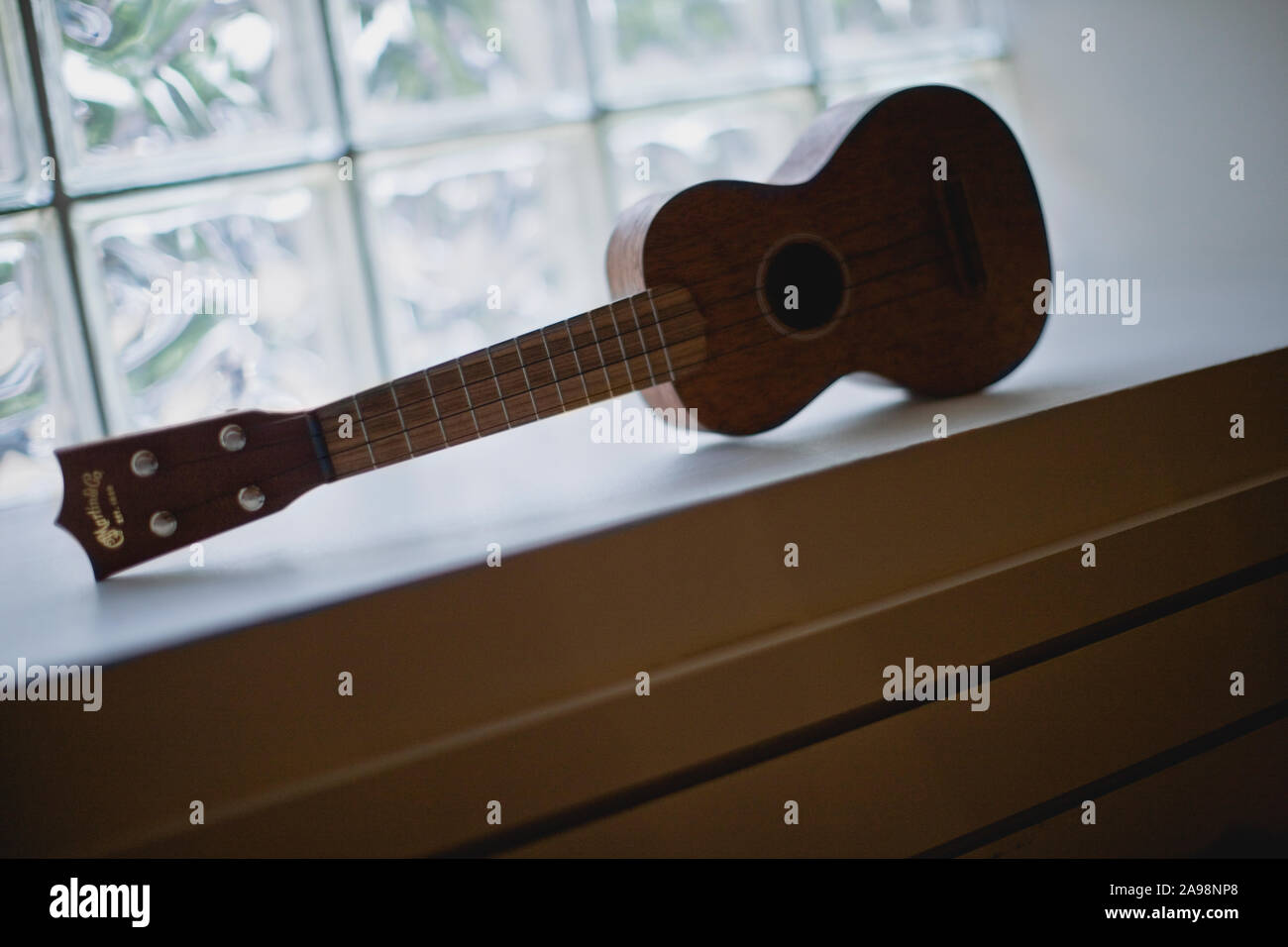 Wooden ukulele on a windowsill. Stock Photo