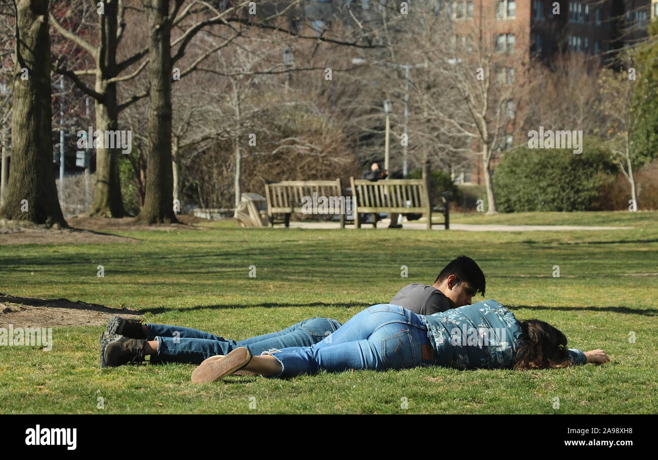 Washington, DC / USA - March 17, 2019: Mixed race couple lie down on the grass and enjoy the sun together Stock Photo