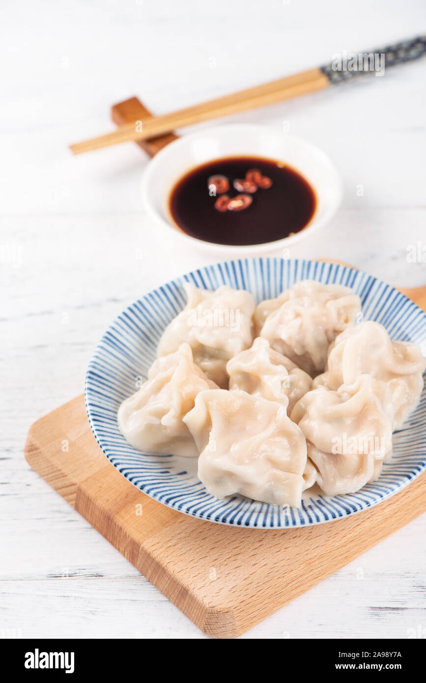 Fresh, delicious boiled pork, shrimp gyoza dumplings on white background with soy sauce and chopsticks, close up, lifestyle. Homemade design concept. Stock Photo
