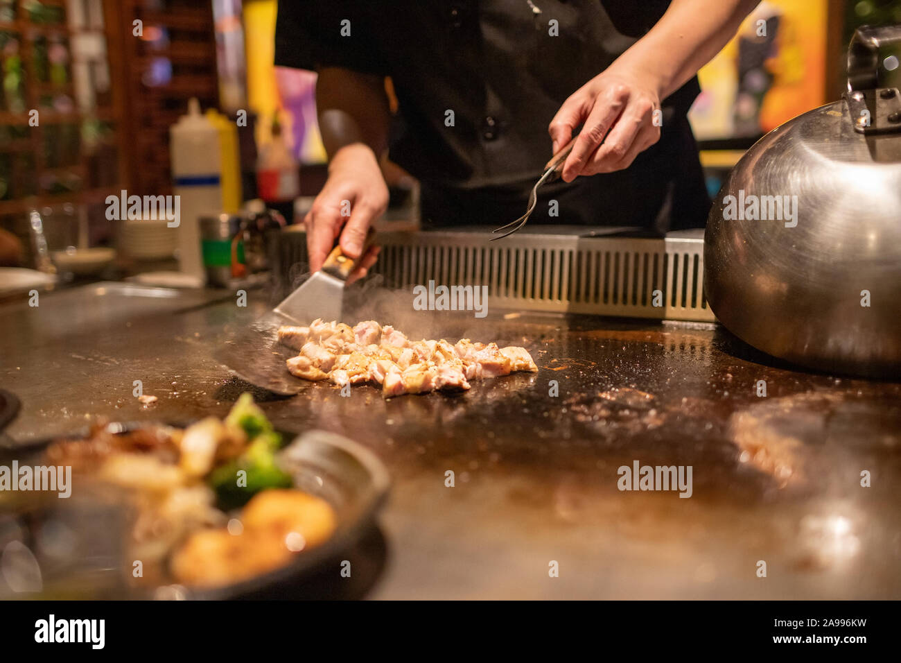 Teppanyaki chef cooking Japanese Teriyaki Chicken on hot metal plate