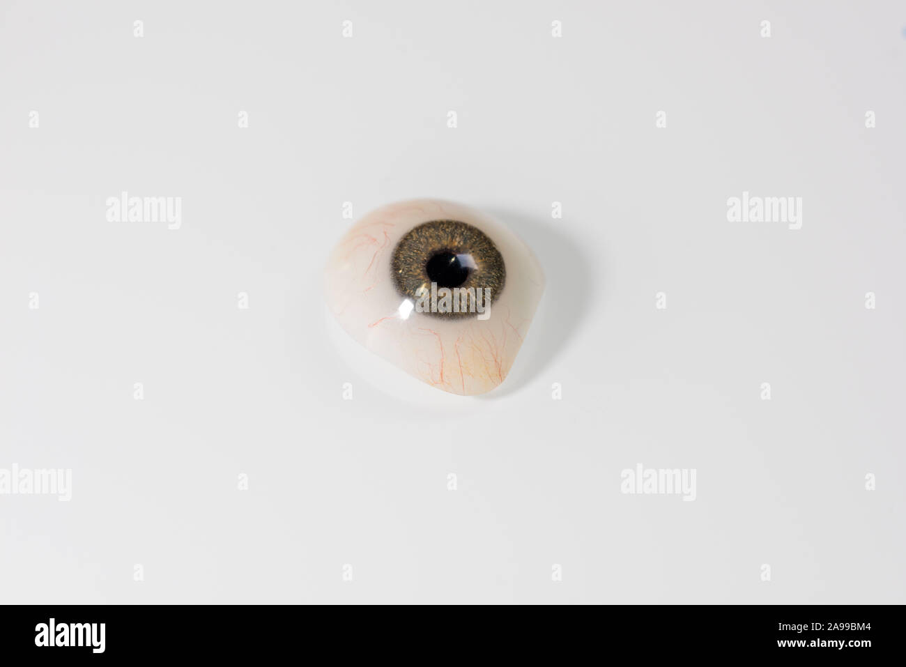 Glass eye prosthetic or Ocular prosthesis with shadow on white glass Stock Photo