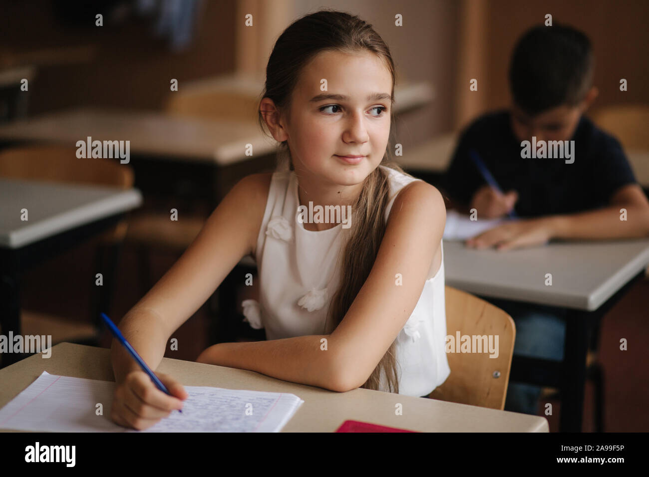 Boy and girl sitting at desk and writing a text Stock Photo