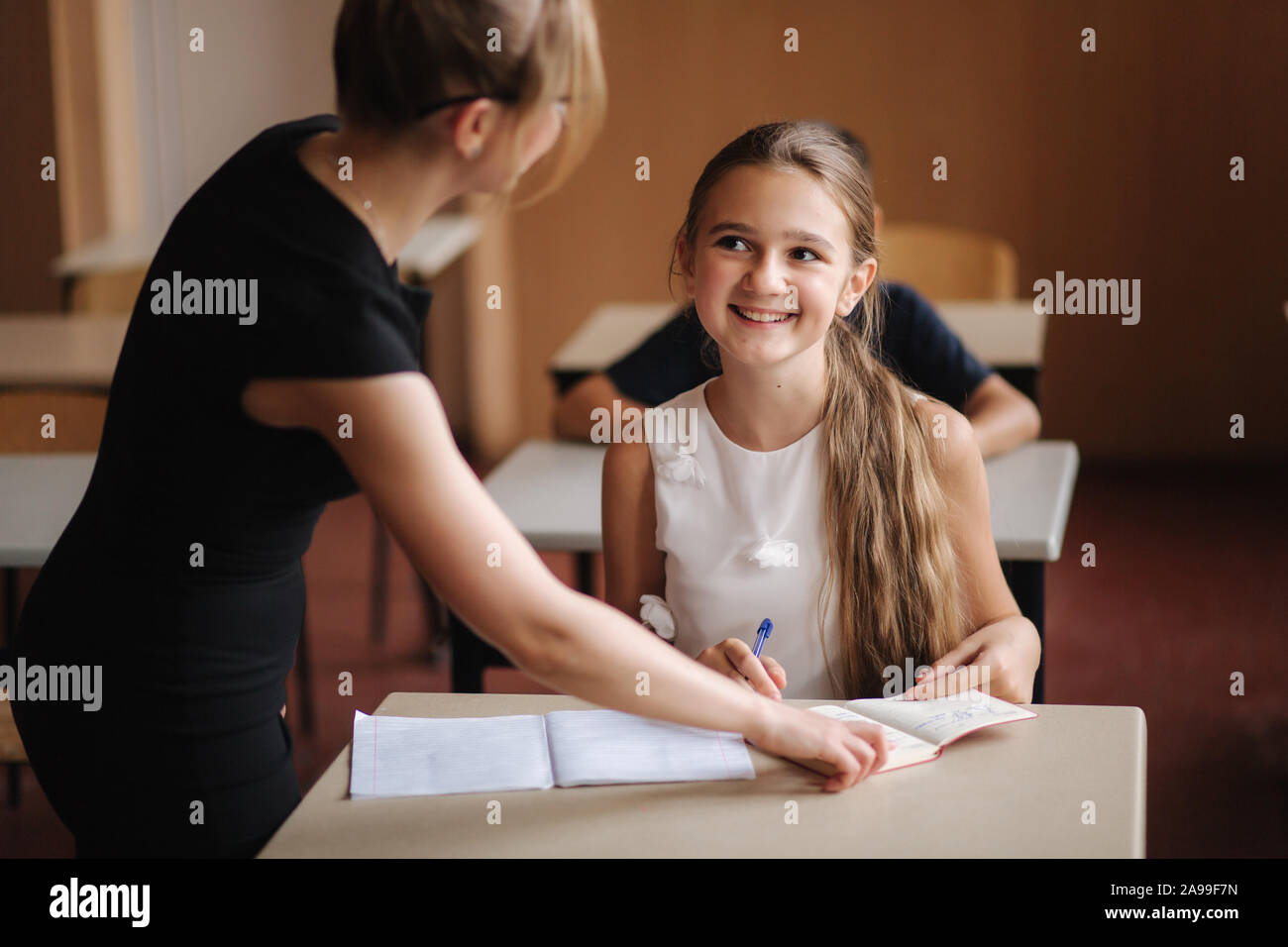 Teacher helping school kids writing test in classroom. education ...
