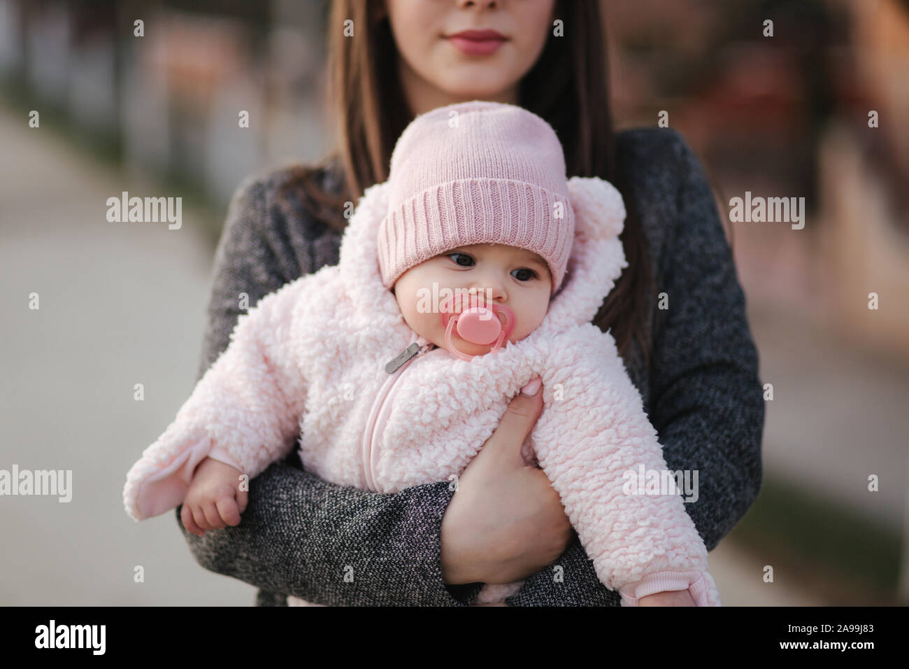 Little baby girl on mother's hands in pink clothes. Cute baby with ...