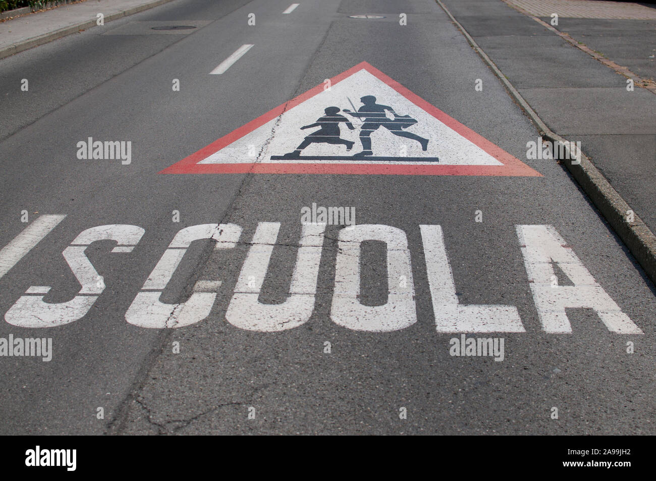 Picture of a huge attention children crossing for school (scuola) warning sign drawn on a street in Caslano, Switzerland Stock Photo