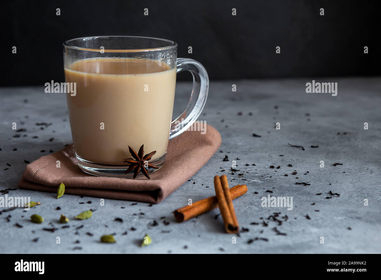 Traditional indian tea with spices in a glass mug on a dark background. Horizontal orientation, copy space Stock Photo