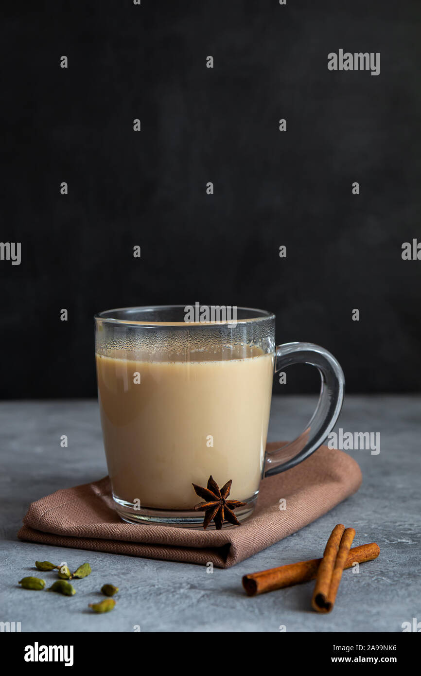 Indian tea masala chai with spices in a glass mug on a dark background. Vertical orientation, copy space Stock Photo