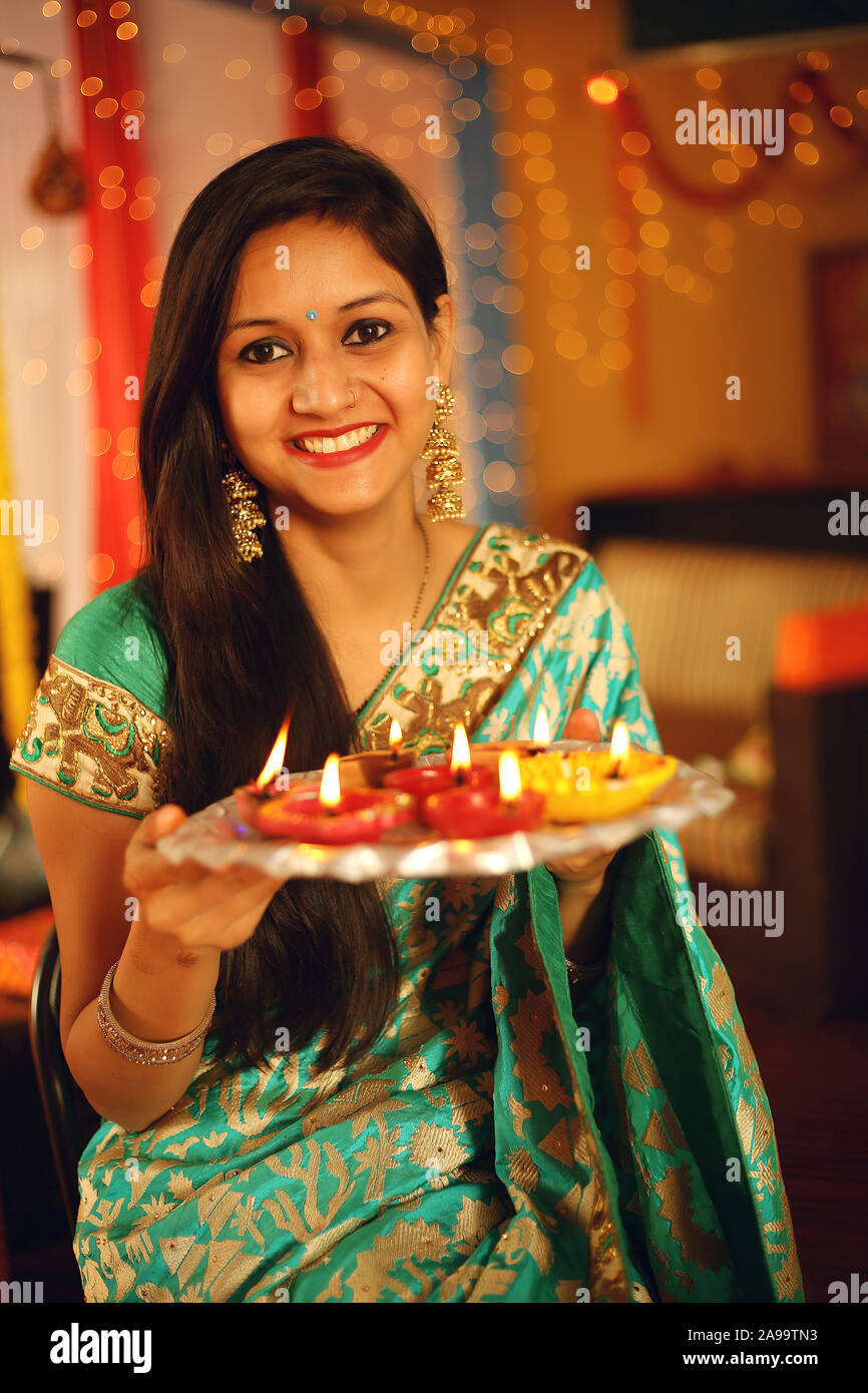 Beautiful Hindu Indian young women lightening Deepa on Diwali day. Stock  Photo | Adobe Stock