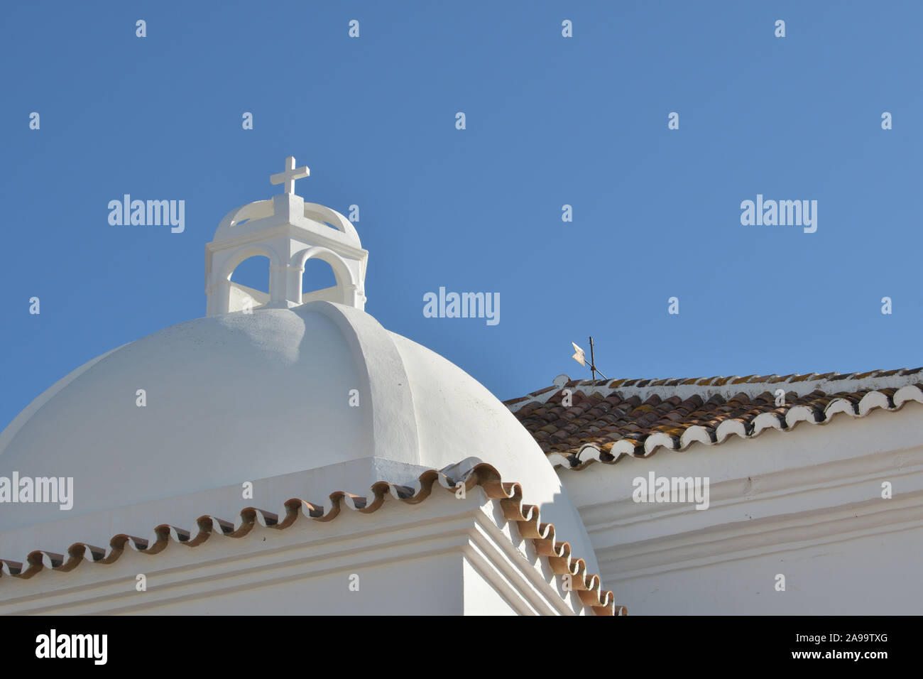 White dome of a typical whitewashed Andalusian church with cross on top Stock Photo
