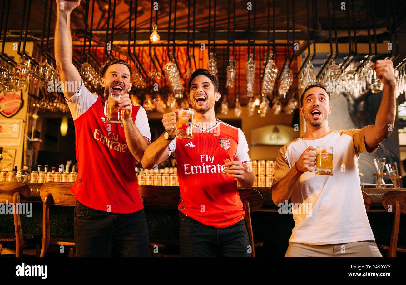 Party excited arsenal fans watching soccer with Ganzberg Beer in the pub Stock Photo