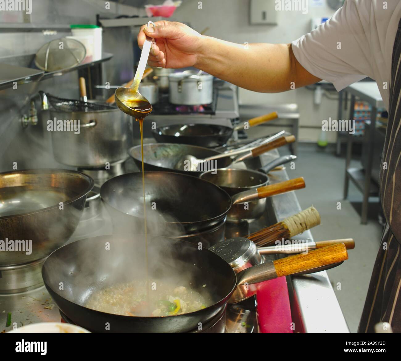 Thai restaurant kitchen detail, chef cooking with woks Stock Photo - Alamy