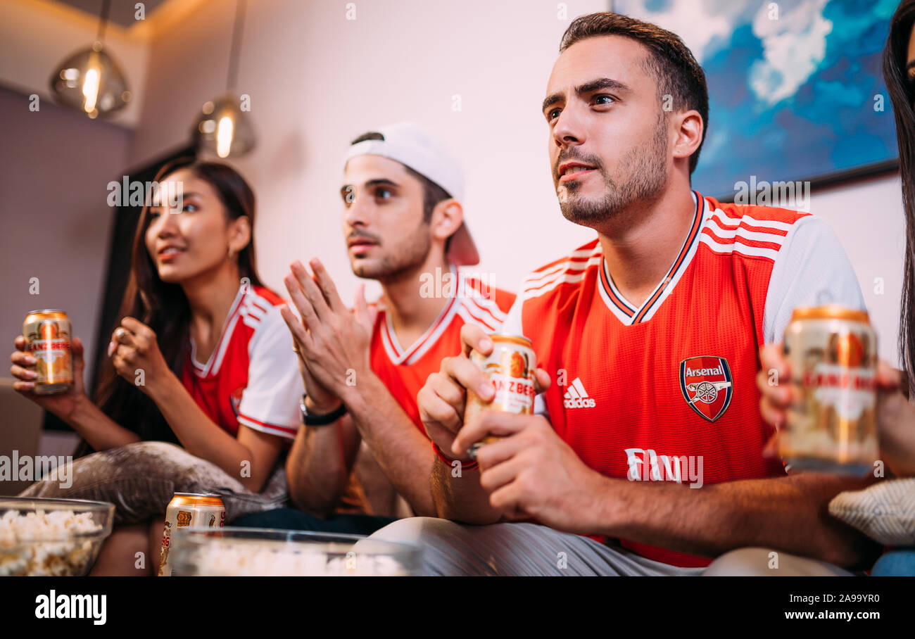 Happy friends or arsenal fans watching soccer on tv and drinking Ganzberg beer celebrating victory at home Stock Photo