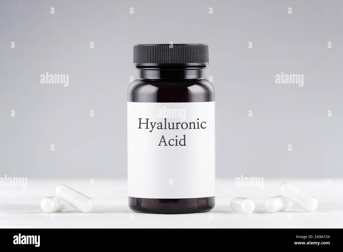 nutritional supplement hyaluronic acid bottle and capsules on gray Stock Photo