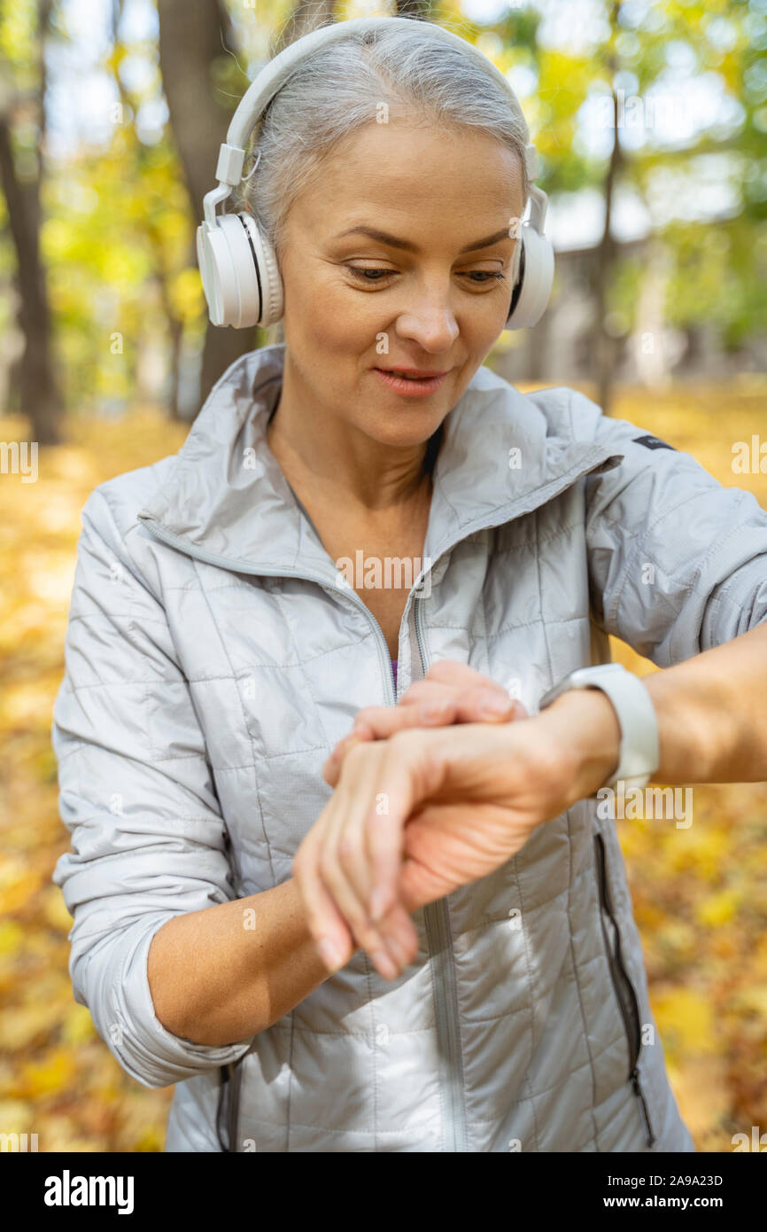 Mature pleasant woman checking her pulse outside Stock Photo