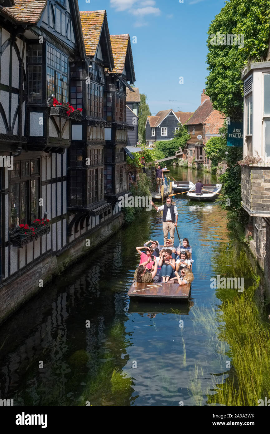 CANTERBURY, UK, - JULY, 11, 2019: Tourists enjoy a punt ride on the River Stour as they pass the 16th Century Old Weavers House in Canterbury, Kent, U Stock Photo