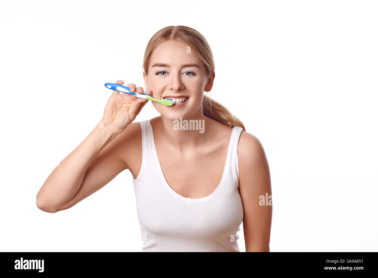 Attractive woman practicing dental hygiene brushing her teeth with a toothbrush and toothpaste to prevent tooth decay or caries , isolated on white Stock Photo