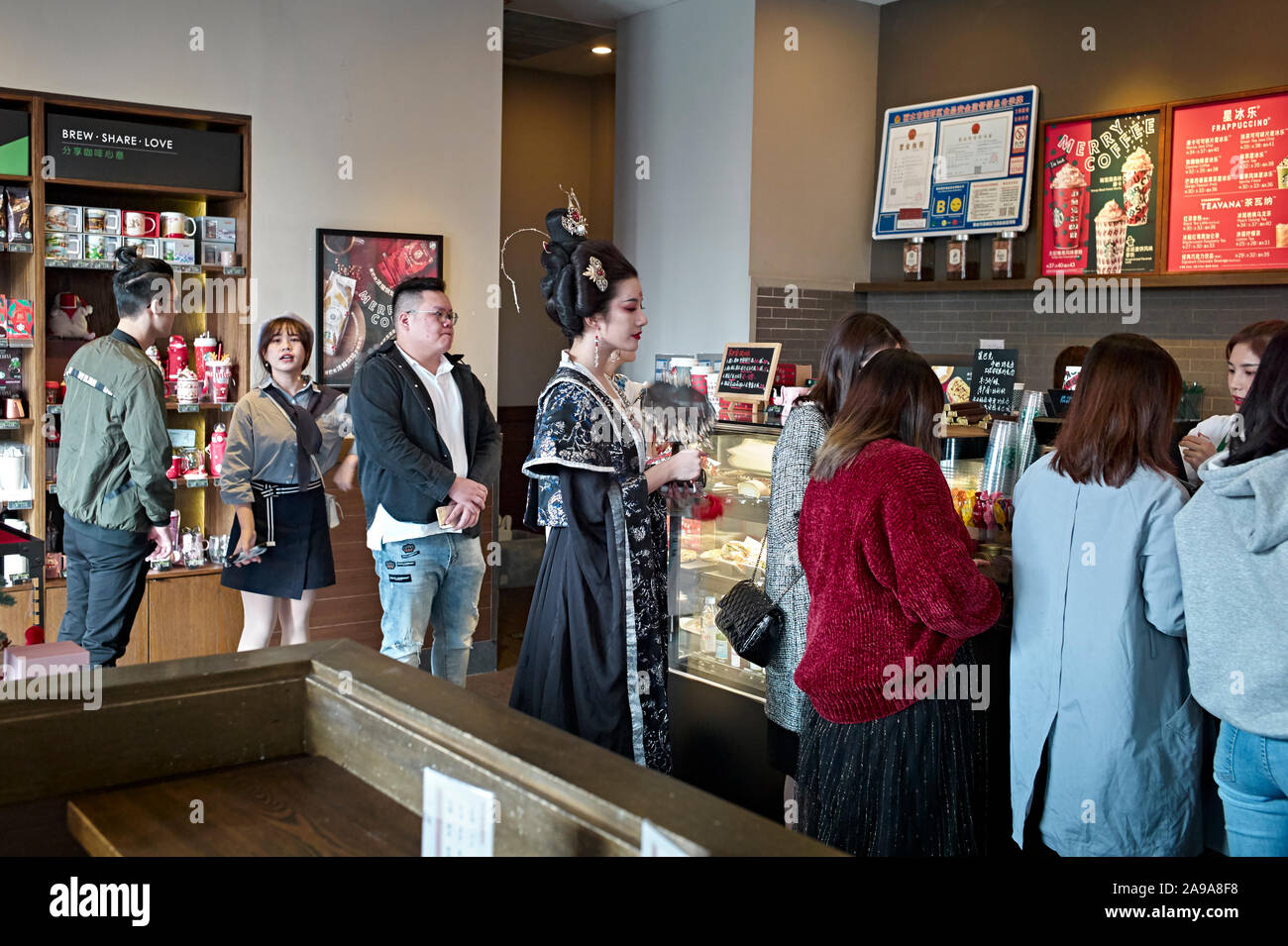 Traditional Chinese dressed female waiting in line at Starbucks coffee in Lishui, Zhejiang Province China, Stock Photo