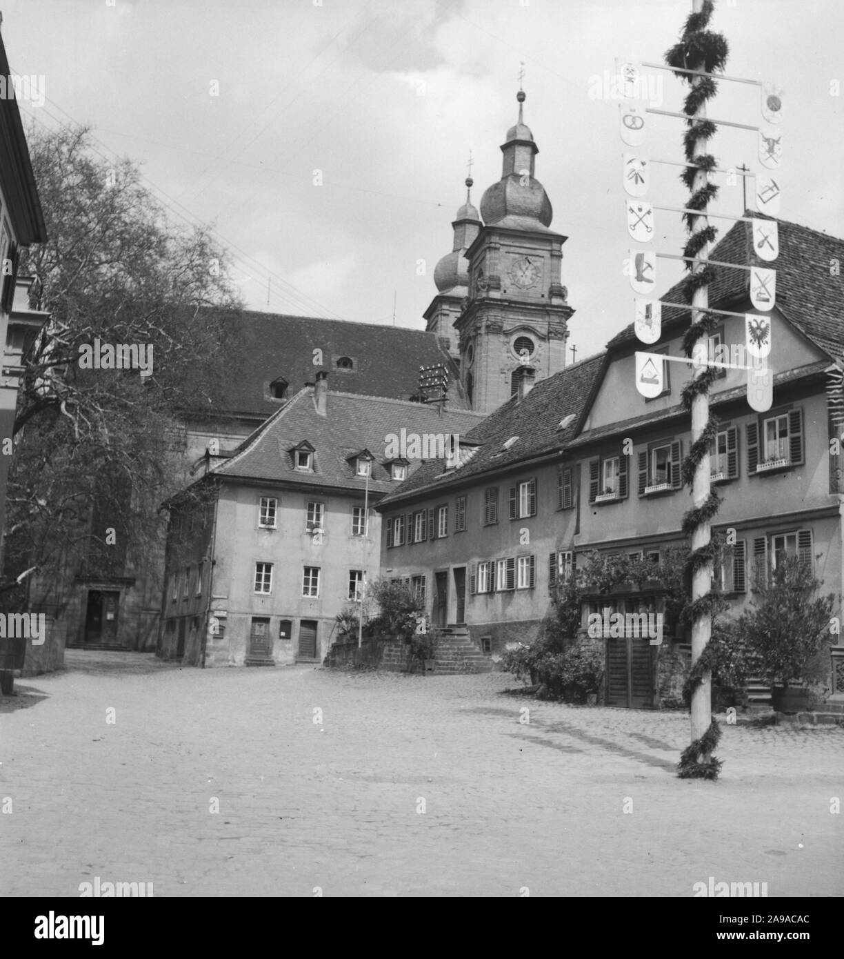 Catholic parish church St. Gangolf with Maypole in Amorbach, German Empire 1930s. Stock Photo