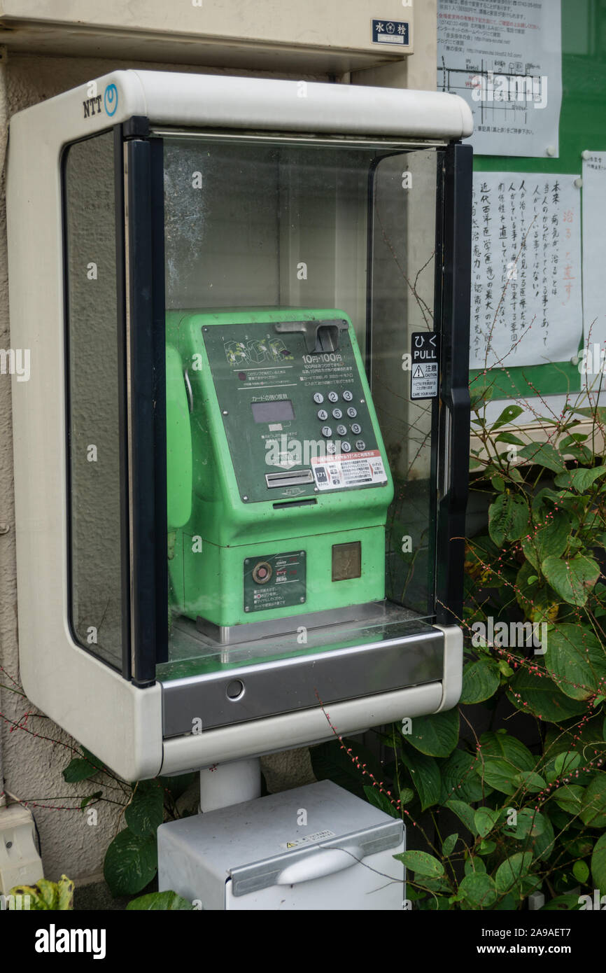 Old green Japanese public telephone in a cabinet at the side of the street Stock Photo