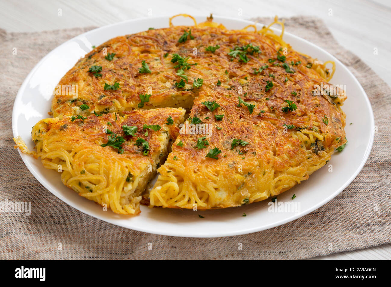 Homemade spaghetti omelette on a white plate, side view. Close-up. Stock Photo