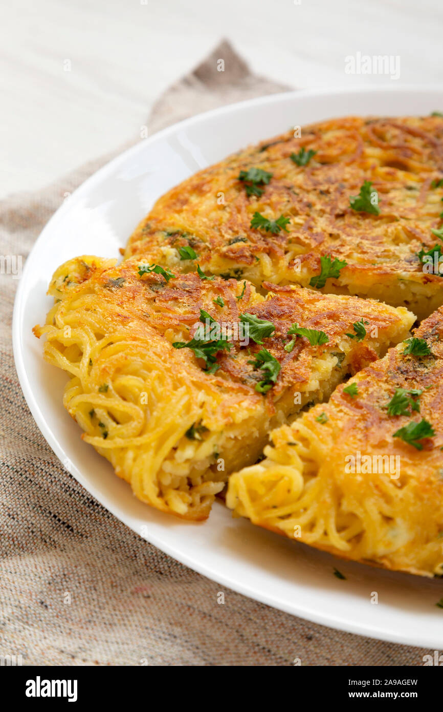 Homemade spaghetti omelette on a white plate, low angle view. Close-up. Stock Photo