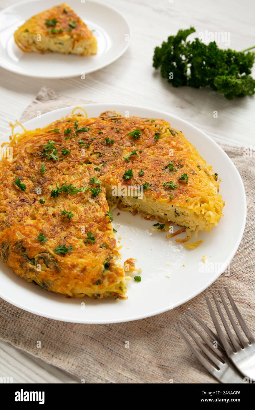 Homemade spaghetti omelette on a white plate, low angle view. Closeup. Stock Photo